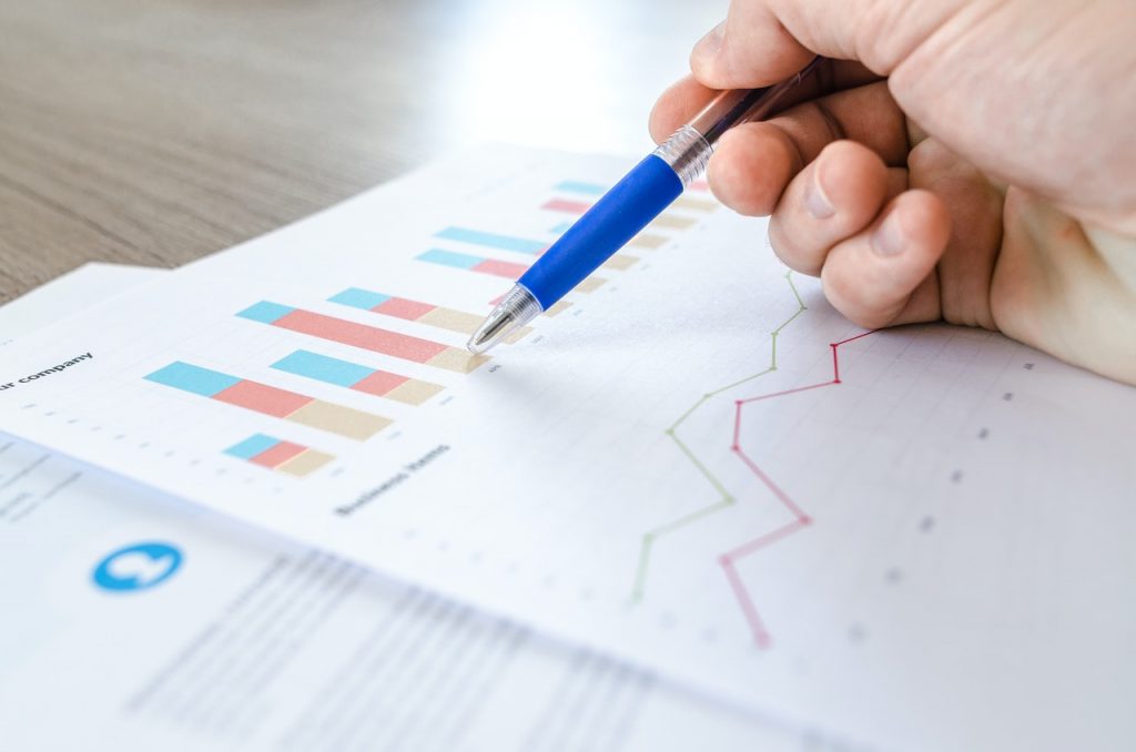 Focused hand crafting a business continuity plan, with charts and graphs in the background, highlighting our meticulous approach to cybersecurity strategies